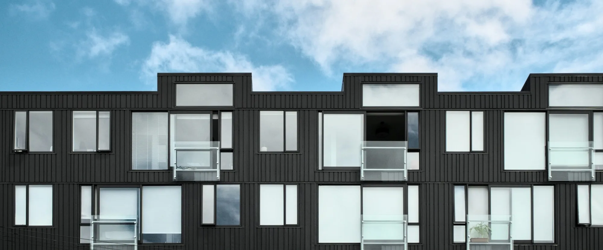 Façade en bardage vertical noir d’un immeuble résidentiel contemporain