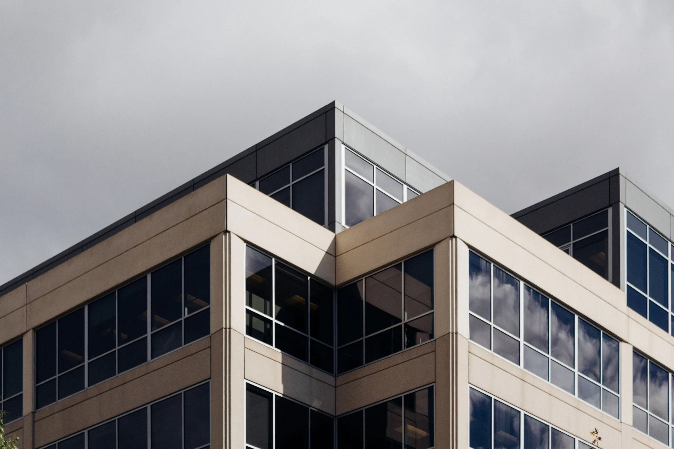 Angle d’un immeuble contemporain, pierre claire et fenestration sombre