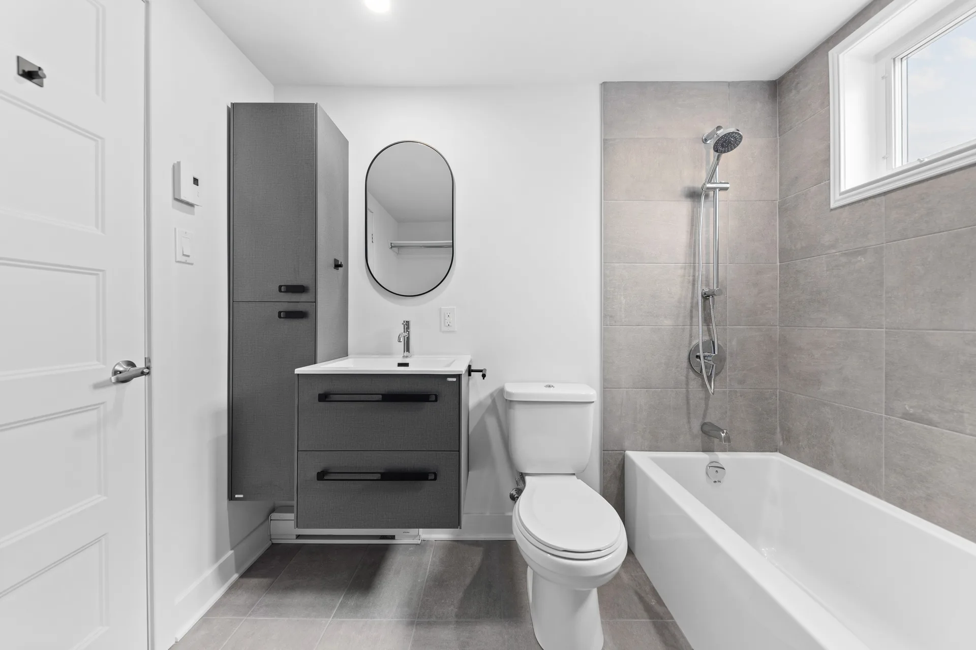 La salle de bain : vanité suspendue, grand miroir et baignoire