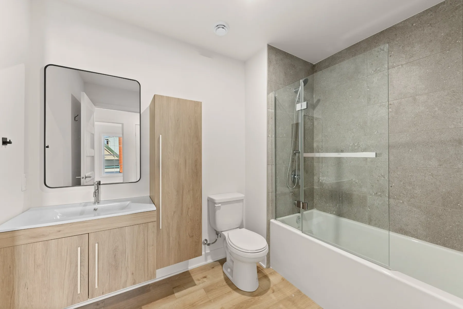 La salle de bain, sa vanité, sa colonne de rangement et sa baignoire-douche